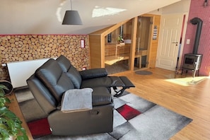 Una sala de estar moderna con un sofá modular, una chimenea y una pared de madera con leña.