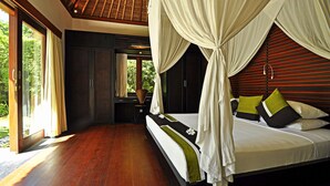 A bedroom with a large bed, wooden flooring, and a view of greenery outside. - Two Bedrooms Villa With Private Pool, Large Landscape Garden and Kitchen (Karangasem)