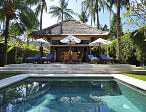 A private pool with lounge chairs and umbrellas, surrounded by palm trees and a thatched-roof structure. - Two Bedrooms Villa With Private Pool, Large Landscape Garden and Kitchen (Karangasem)