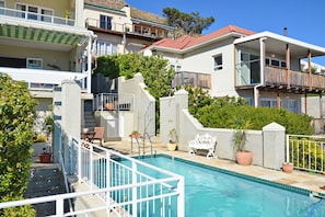 A residential building with a swimming pool, balconies, and a staircase leading to an upper floor.