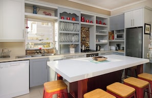 A modern kitchen with a central island, bar stools, a dishwasher, and a refrigerator.