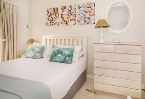 A bedroom with a bed, a dresser, a mirror, and artwork on the wall.
