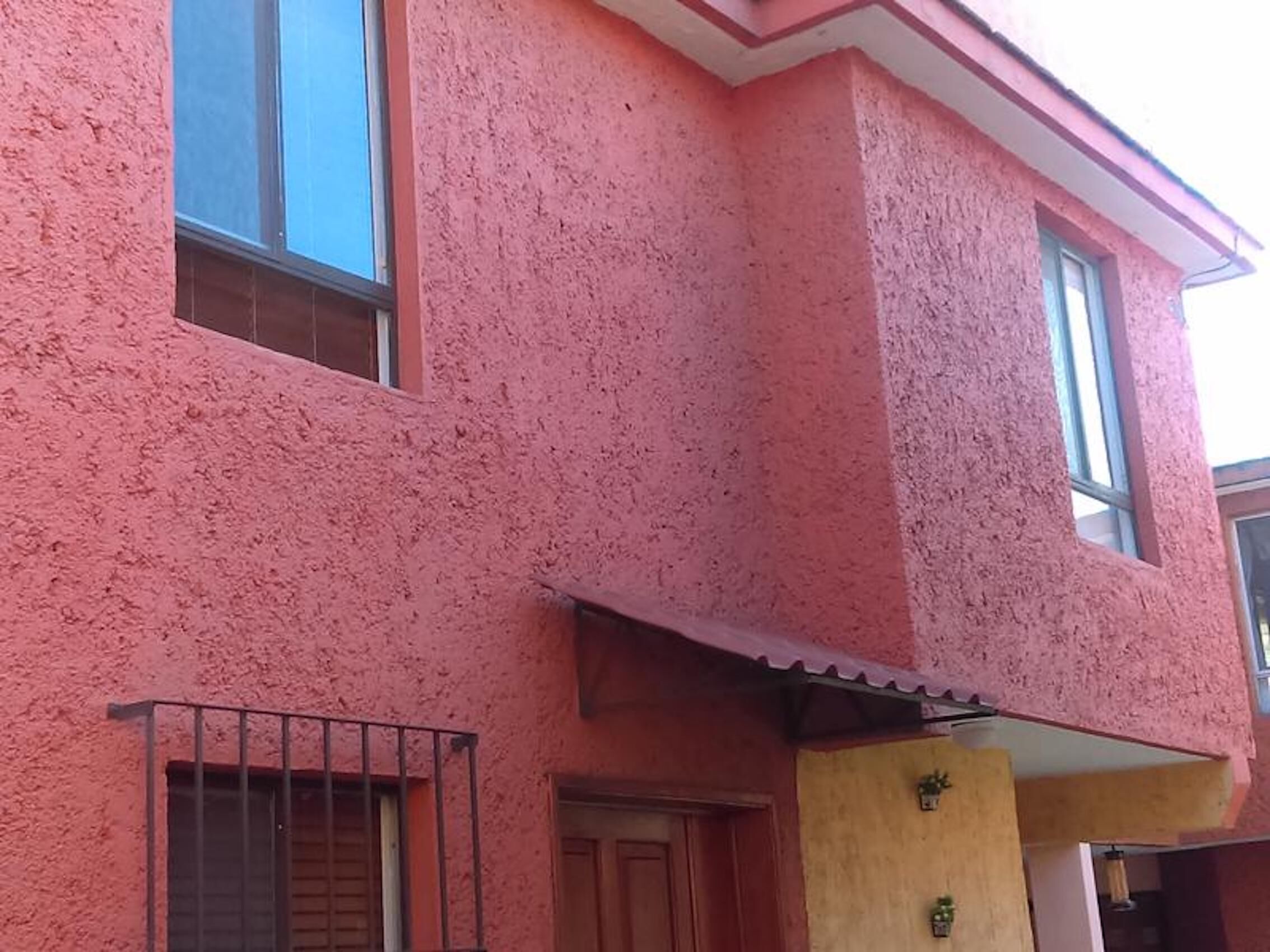 Een roze gebouw met balkon, een deur en ramen.