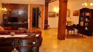 Ein geräumiges Wohnzimmer mit Kamin, Ledersofa, Holzregalen und einem Essbereich mit Tisch und Stühlen.