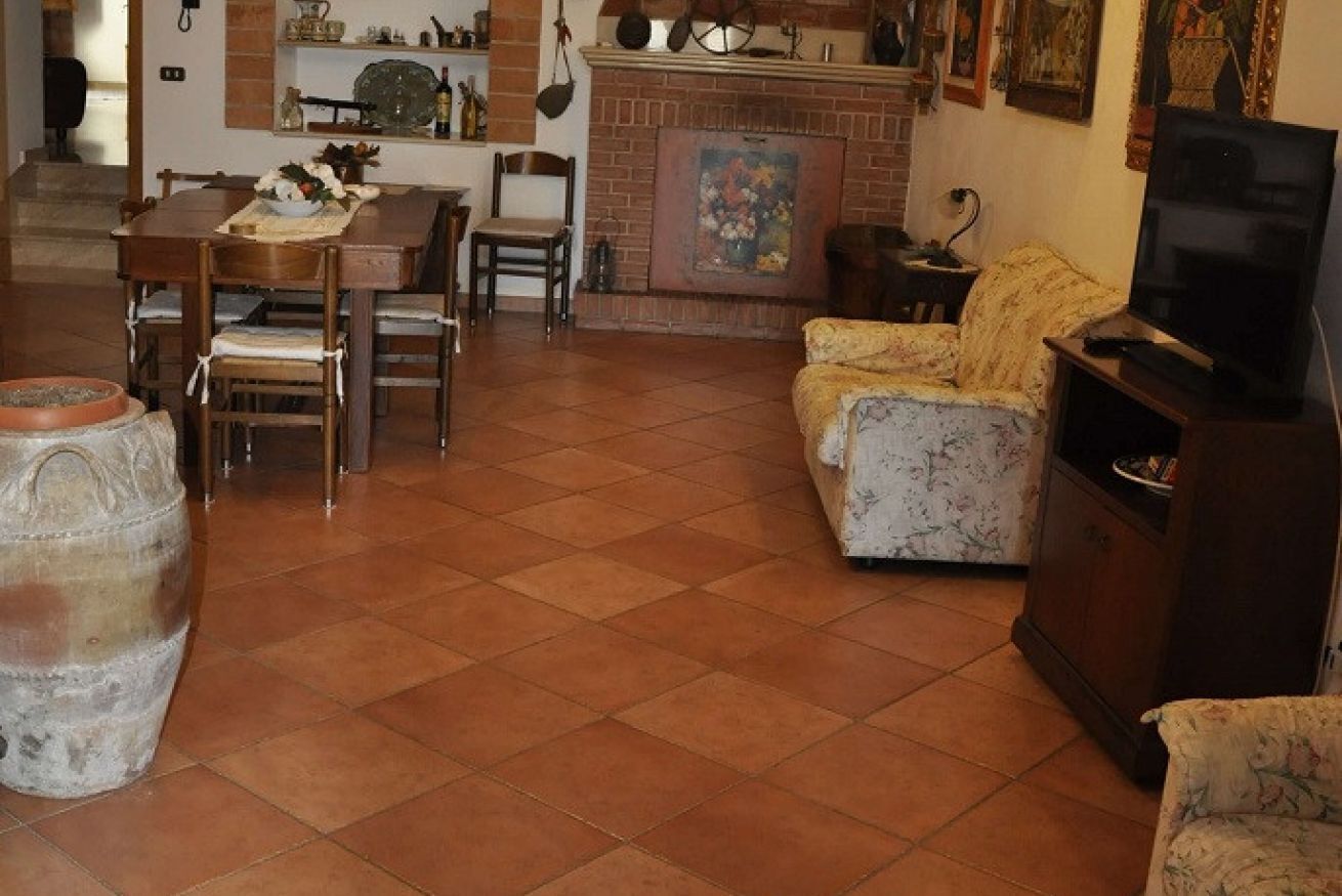 Una sala de estar con chimenea, un comedor con sillas y un televisor sobre un mueble.
