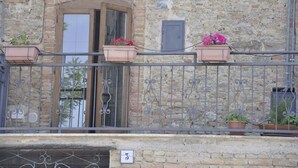 Ein Gebäude aus Stein mit Balkon, Blumentöpfen und einer Tür.