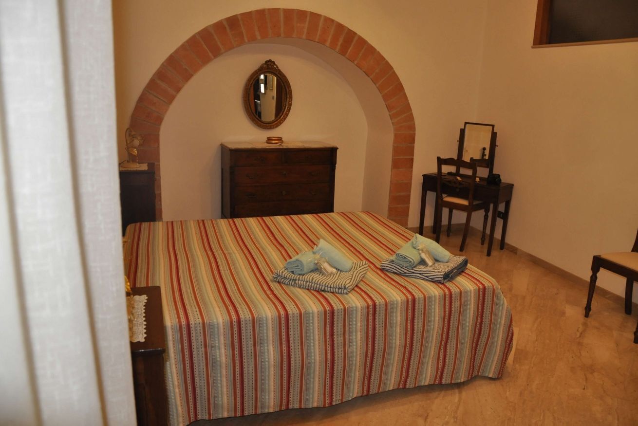 A bedroom with a bed, a dresser, a mirror, and a chair.