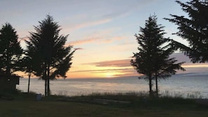 A coastal landscape with trees and a sunset over the water. - Ocean View Tent Site T3 (Port Angeles)