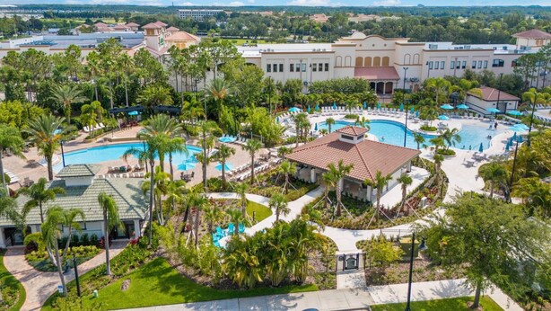 A resort with multiple swimming pools, palm trees, and a large building in the background.