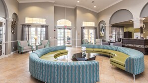 A spacious lobby with a curved seating area, a reception desk, and large windows allowing natural light. - Orlando Palms Deluxe 3 Bedroom Condo by RedAwning (Orlando)