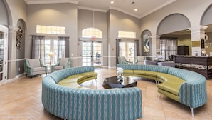 A spacious lobby with a curved seating area, a reception desk, and large windows allowing natural light.