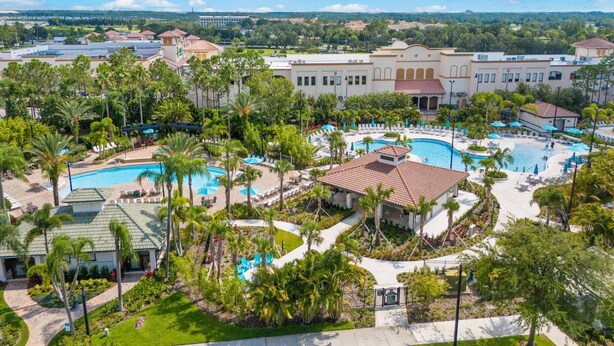 Un resort con varias piscinas, palmeras y un edificio grande con techo rojo.
