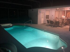 An indoor swimming pool with a clear water edge, a diving board, and a seating area with chairs and a table. - Little Mermaid Villa- Beautiful Private Villa (Haines City)