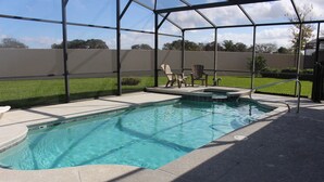 A swimming pool with a covered area, a small deck, and a few chairs. - Little Mermaid Villa- Beautiful Private Villa (Haines City)