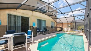 Une piscine intérieure dotée d’un toit en verre, entourée de chaises longues et de tables.