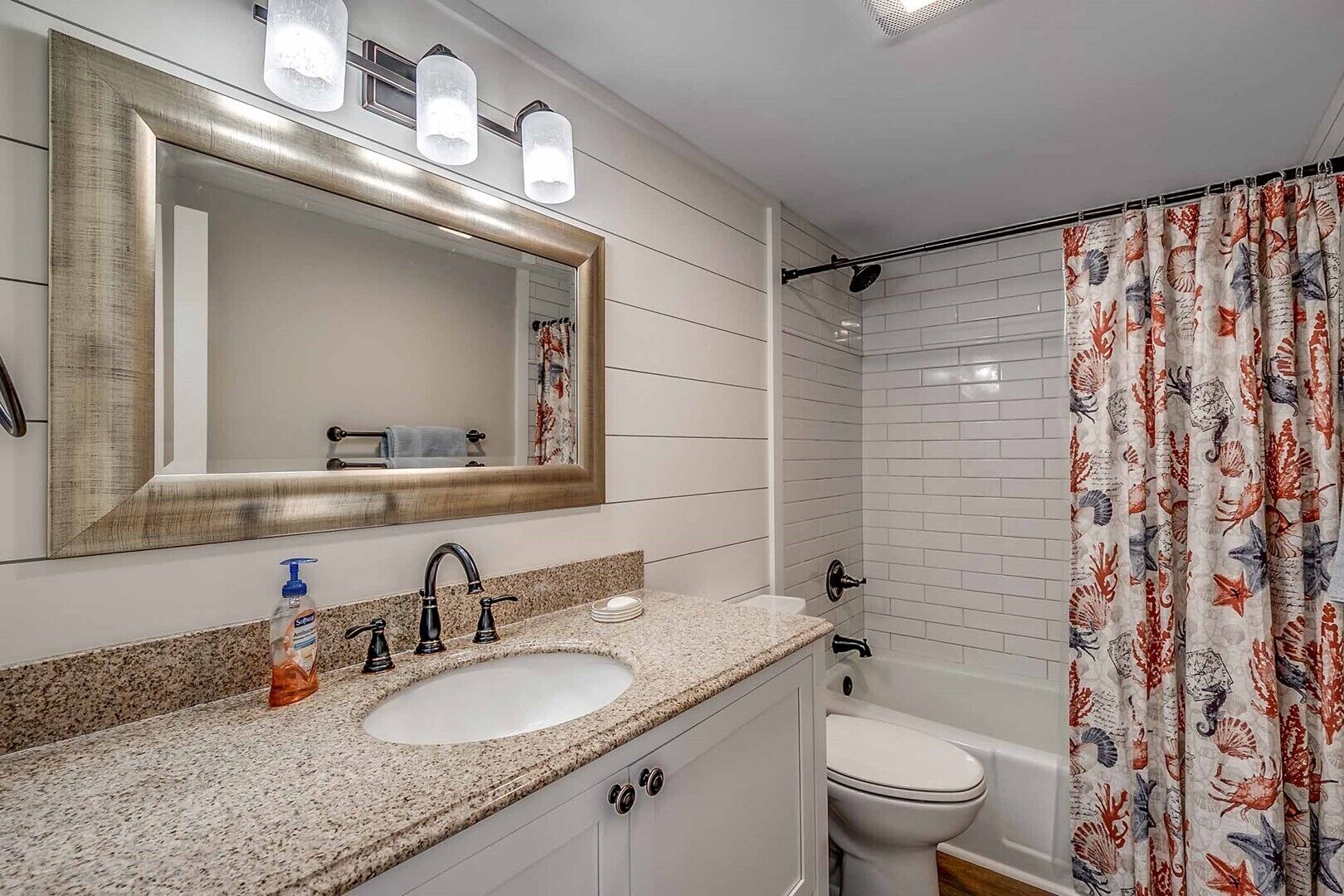 Une salle de bain dotée d’un meuble-lavabo à deux vasques, d’un grand miroir et d’un rideau de douche orné de motifs représentant des créatures marines.