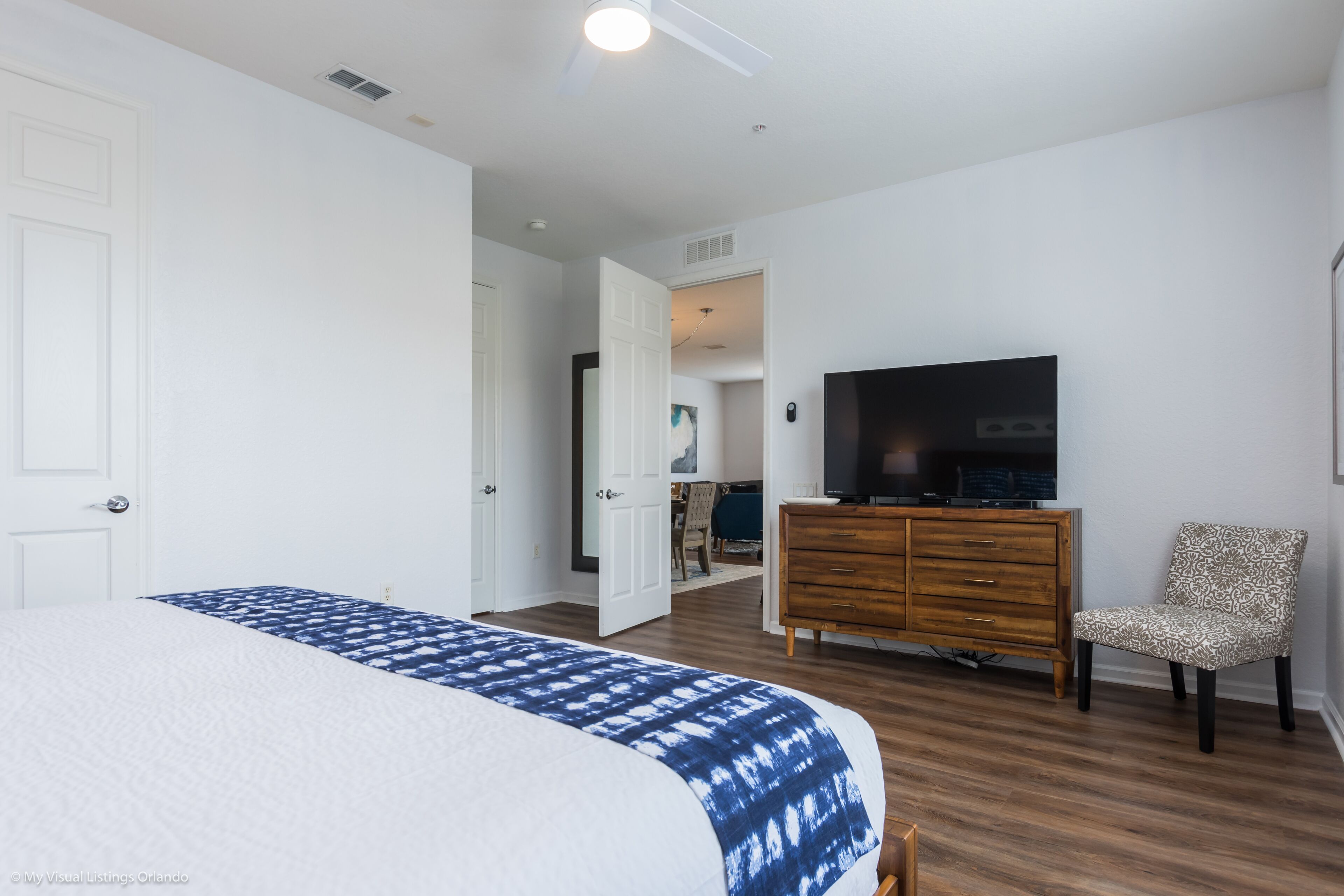 A bedroom with a bed, a television, a dresser, and a chair.