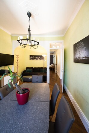A dining area with a table, chairs, a red potted plant, and a chandelier. - Beautiful 51m² apartment with garage - Charpennes (Lyon)