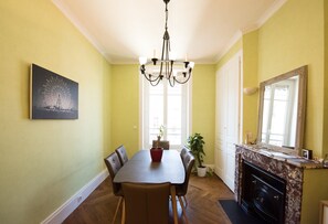 A dining room with a chandelier, a fireplace, and a large window. - Beautiful 51m² apartment with garage - Charpennes (Lyon)