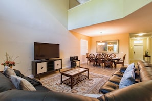 Una sala de estar con sofá, mesa de centro, televisor y un comedor con sillas y una mesa.
