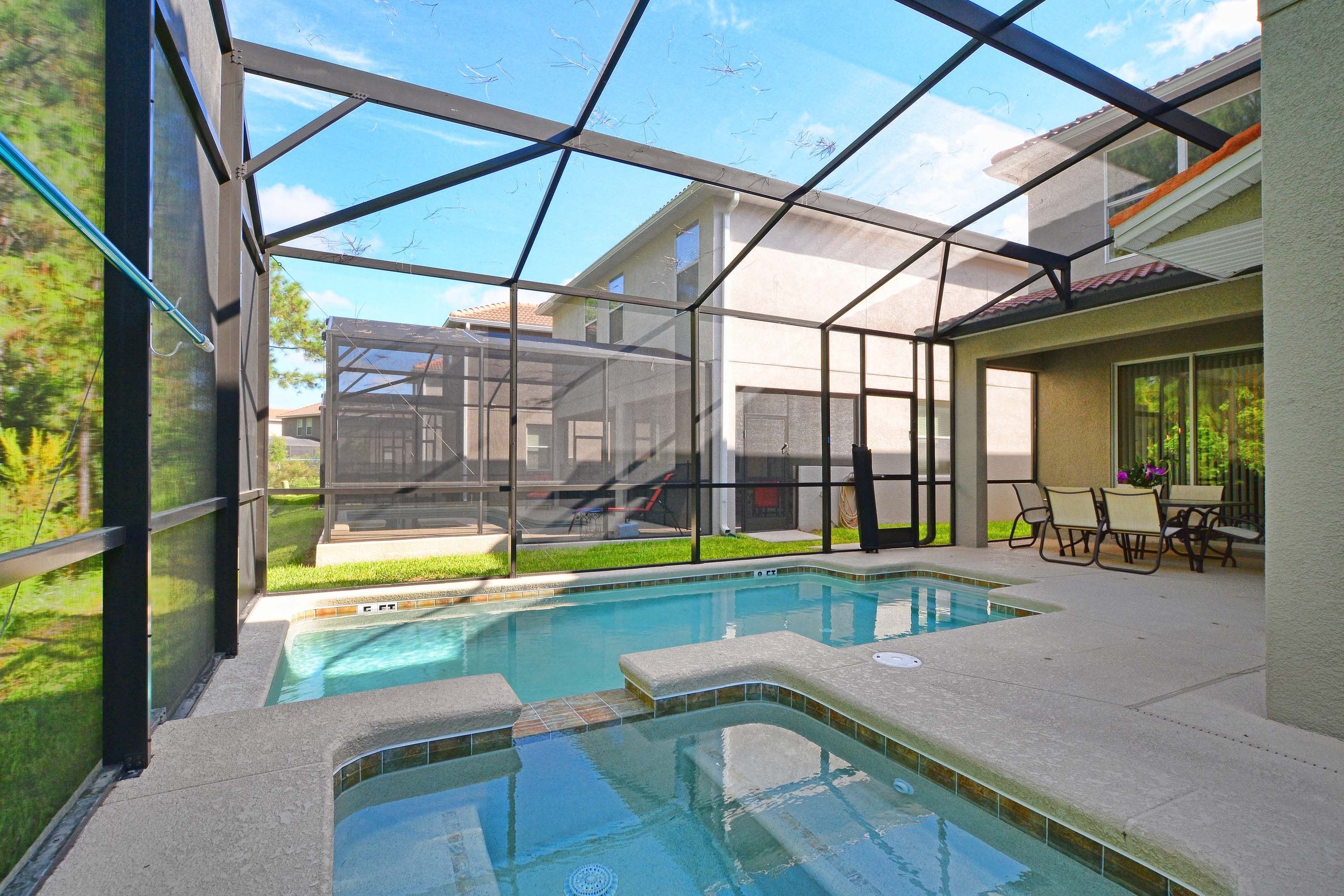 Ein Schwimmbad mit Glasveranda, Sitzgelegenheiten im Freien und Blick auf die Nachbarschaft.