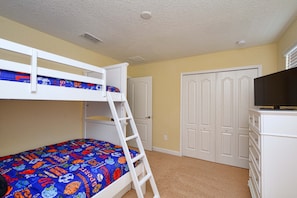 A bunk bed with a ladder, a dresser, and a wardrobe in a room with yellow walls.