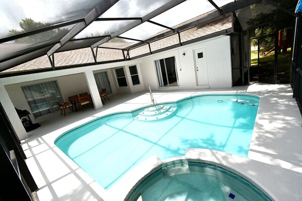 A swimming pool with a sunshade structure, a covered seating area, and a view of a playground. - Greater Groves - 5 Bedrooms House w/pool-5202GG Home by RedAwning (Clermont)
