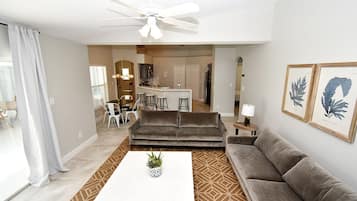 A living room with a sofa, a coffee table, and a ceiling fan.