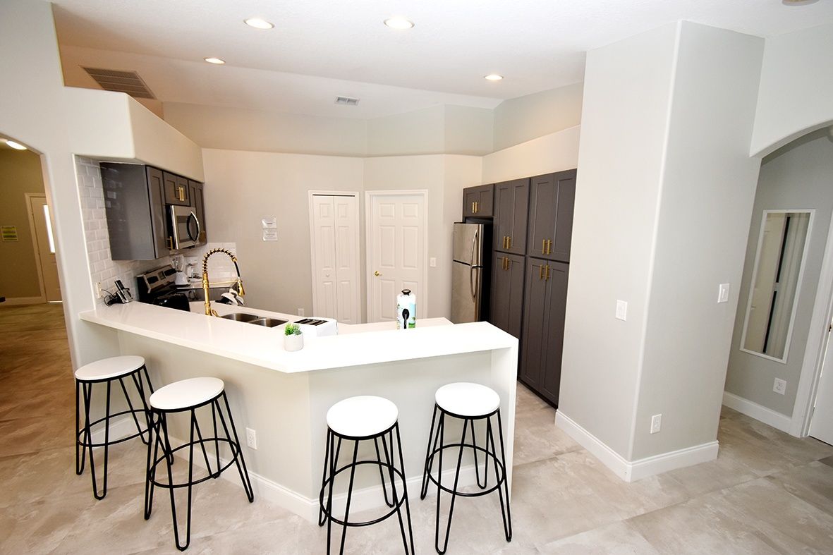 A modern kitchen with a central island, bar stools, and dark cabinetry.