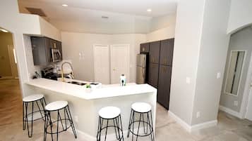 A modern kitchen with a central island, bar stools, and dark cabinetry.