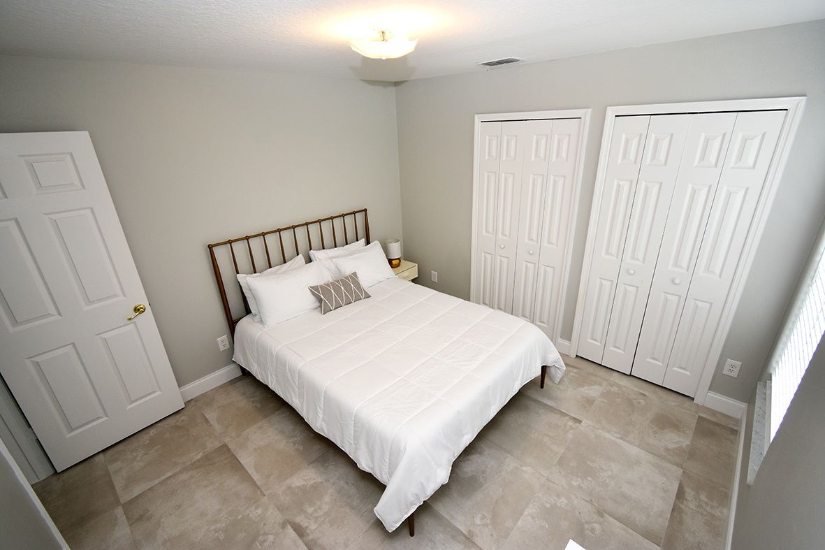 A bedroom with a bed, two white doors, and a light fixture on the ceiling.