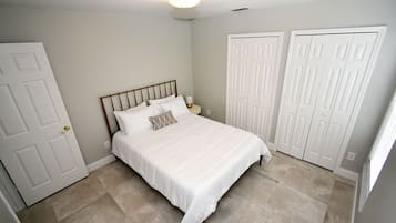 A bedroom with a bed, two white doors, and a light fixture on the ceiling.