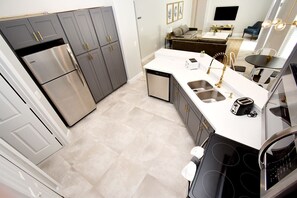 A modern kitchen with stainless steel appliances, a white countertop, and a built-in oven. - Greater Groves - 5 Bedrooms House w/pool-5202GG Home by RedAwning (Clermont)
