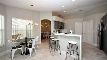 A modern kitchen with a central island, bar stools, and a dining area with a round table and chairs.