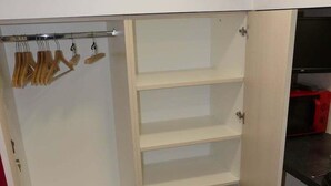 En walk-in garderobe med åbne hylder og et pengeskab.