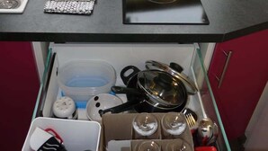 Et køkken med en sort bordplade, en hvid skærebræt, et hvidt viskestykke og en skuffe med køkkenredskaber.