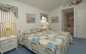 A bedroom with a bed, nightstands, lamps, and two framed pictures on the wall.