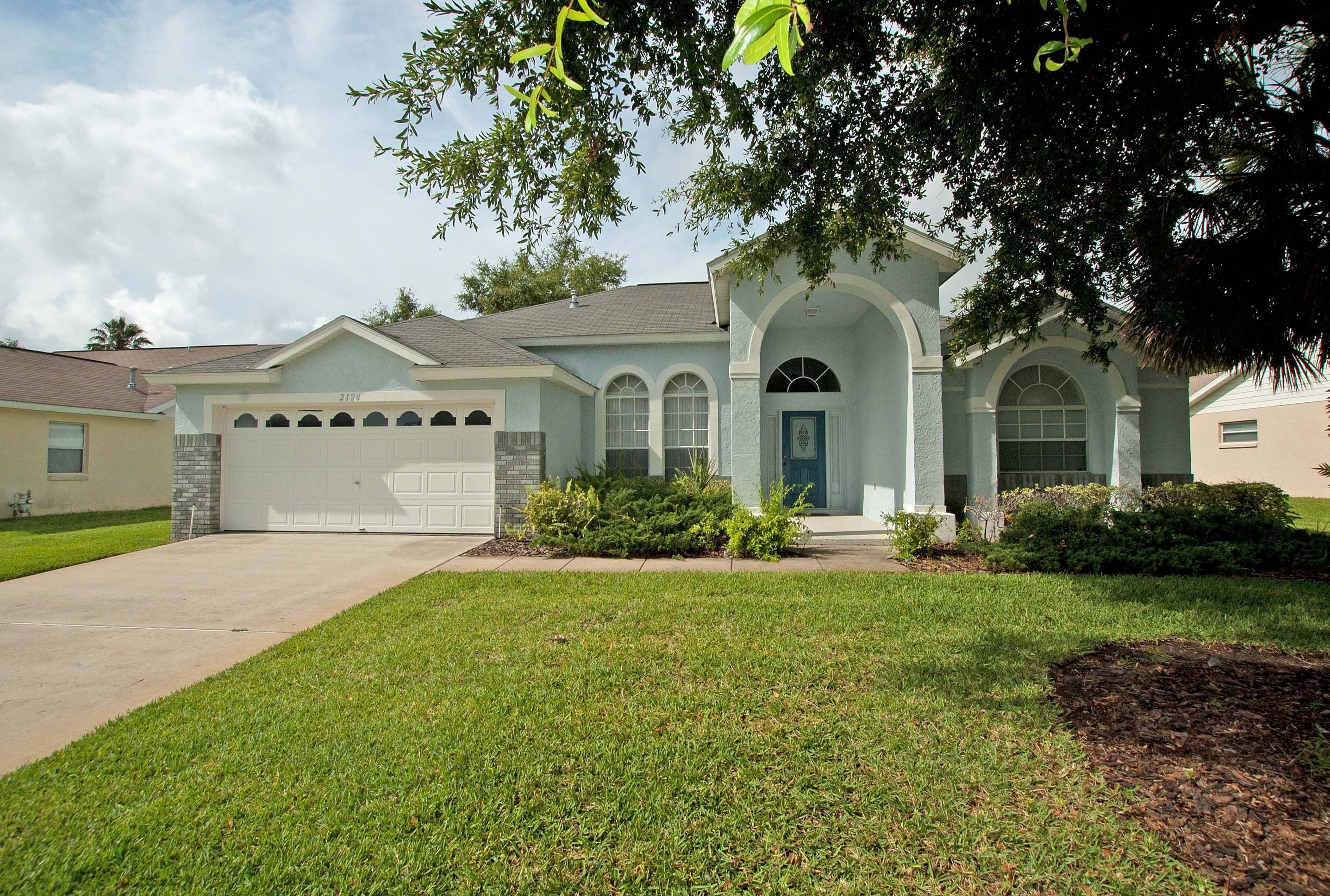 A two-story house with a garage, a front porch, and a well-maintained lawn.