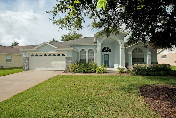 A two-story house with a garage, a front porch, and a well-maintained lawn.