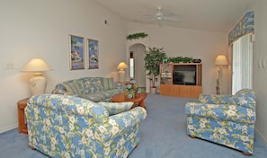 A living room with a sofa, armchair, and a television set.