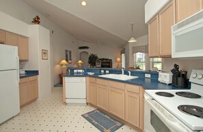 A kitchen with wooden cabinets, a white refrigerator, a dishwasher, a stove, and a microwave. - Greater Groves-4 Bedrooms Home W/pool-5204GG Home by RedAwning (Clermont)