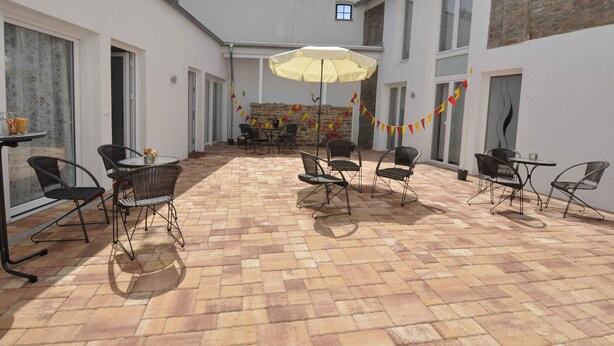 An outdoor patio with tiled flooring, metal chairs, a table, and a yellow umbrella. - Nice apartment on the ground floor for 2 persons (Höxter (Lüchtringen))
