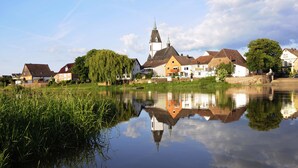 A riverside town with a prominent church, calm water reflecting buildings, and lush greenery. - Nice apartment on the ground floor for 2 persons (Höxter (Lüchtringen))
