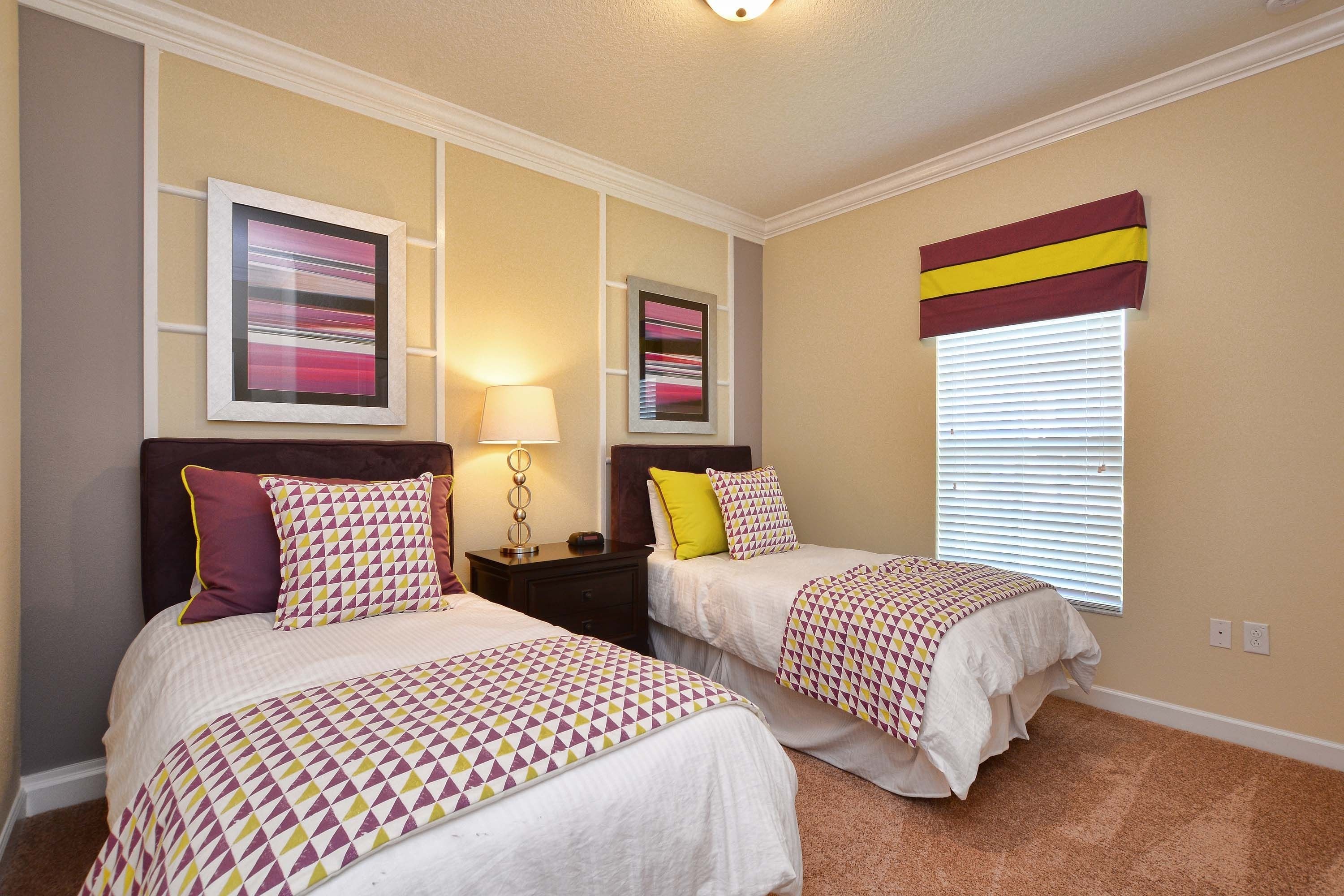 A hotel room with two beds, a nightstand, a lamp, and a window with blinds.