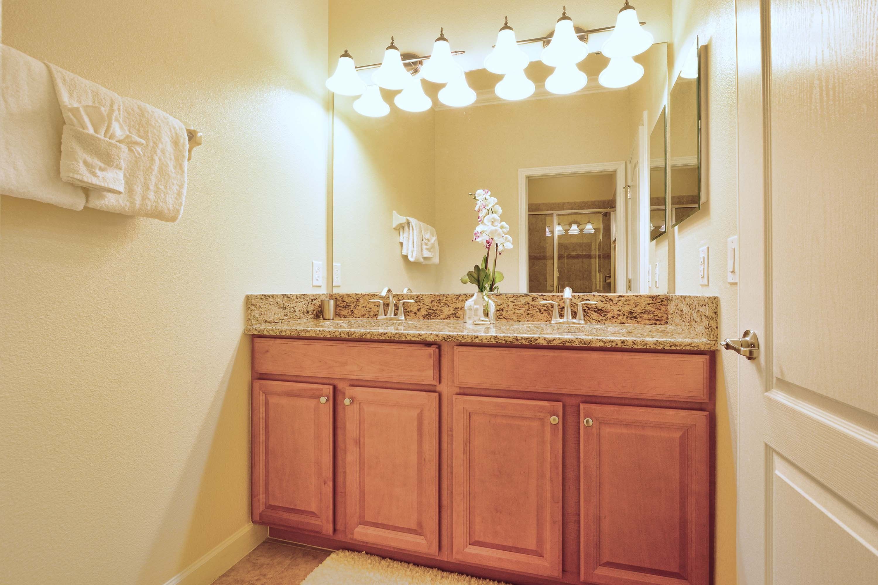 A bathroom with a double vanity, a mirror, and a light fixture above the sink.