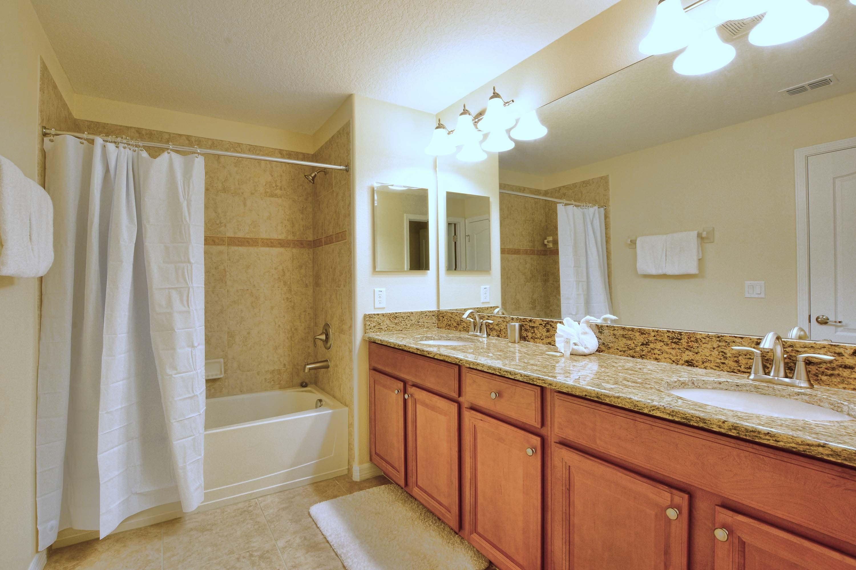 A bathroom with a bathtub, a shower, a sink, and a vanity with a mirror.