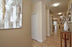 A hallway with a white door, a decorative wall piece, and a vase with flowers on a table.