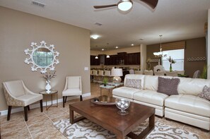A living room with a sofa, chairs, a coffee table, and a decorative mirror.