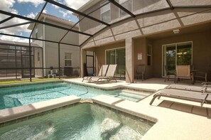 A pool area with a clear view of the sky, a hot tub, and lounge chairs.