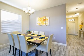 A dining area with a table set for six, chairs, a chandelier, and a wall-mounted painting. - Solterra - 5 Bedrooms House w/pool-7035SR Home by RedAwning (Davenport)